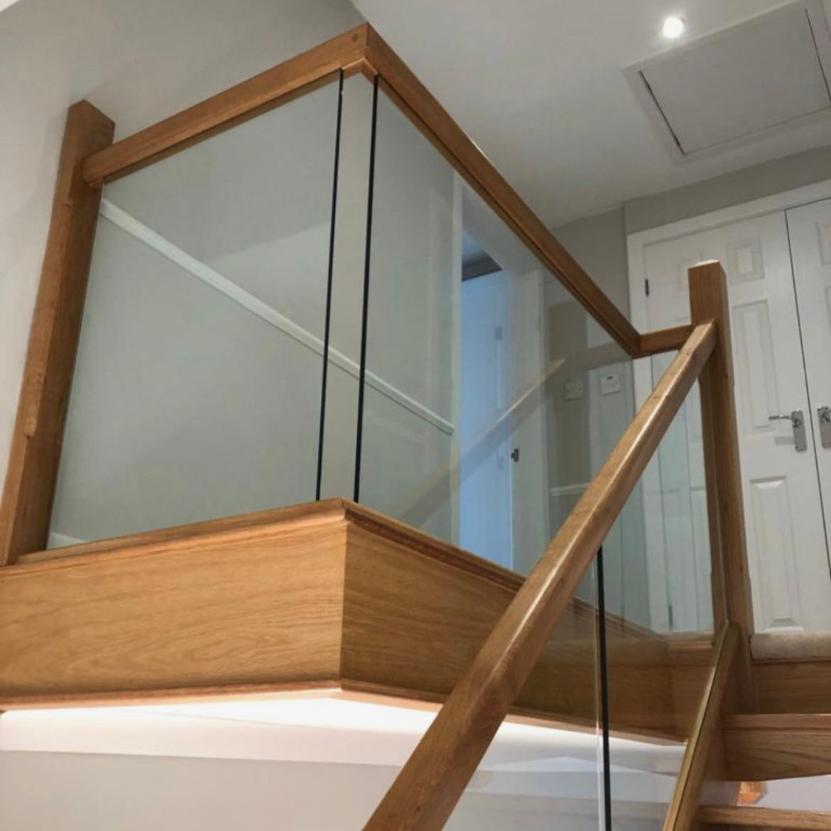 Wooden staircase with glass balustrade in a modern interior setting.